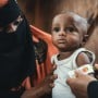 Community health worker assessing infant in Yemen 