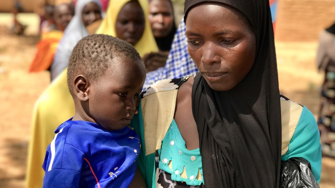 Mum-of-four Tsahara Maidagi (27) and her 19-month-old son Mamane wait to receive an emergency monthly money transfer and fortified flour at a Concern distribution in Sarkake, Tahoua. “The money helps our family. It is used mainly to buy food, like millet and vegetables for us to eat,” she said. Photographer: Darren Vaughan/ Concern Worldwide.