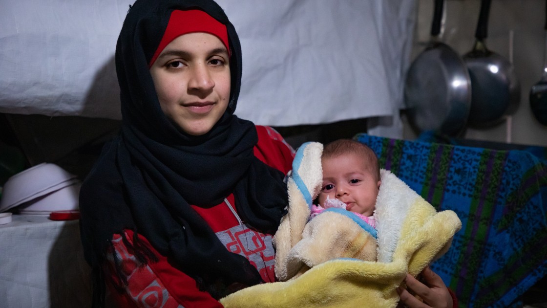 Wafdeh* (20) with her youngest daughter Rajaa* wrapped in a thermal blanket in their makeshift kitchen. Photo: Gavin Douglas/ Concern Worldwide.