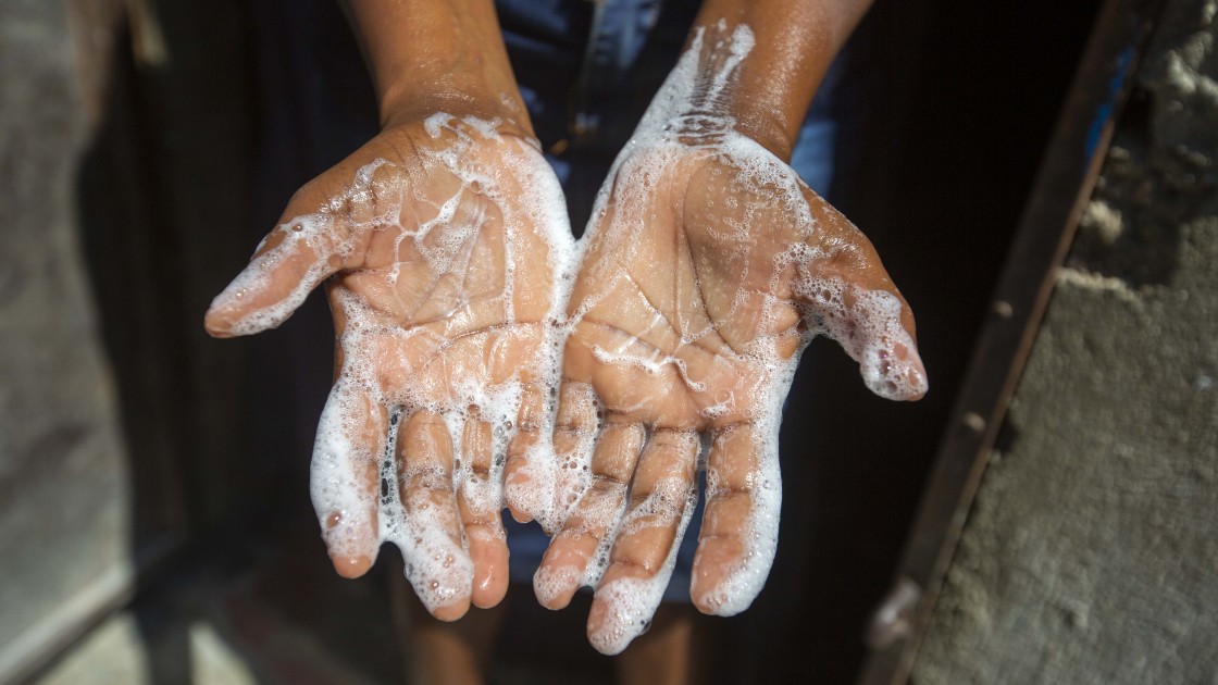 Rosette Mesalien 34 washes her hands with liquid soap she made with help from Concern in front of their home in Cite Soleil slum, a district of Port-au-Prince, Haiti.