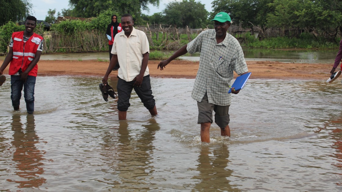 A Concern aid worker walking through flood water in Sudan