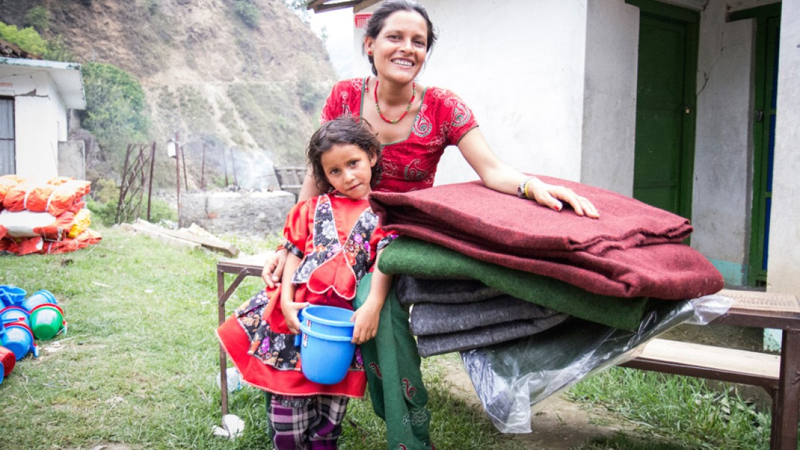 Chameli Darji with her youngest daughter, Apita, with the items they received at a Concern Worldwide and Rural Reconstruction Nepal (RRN) distribution in Talamarang VDC in Sindhupalchok district, Nepal. Photo taken by Crystal Wells / Concern Worldwide.