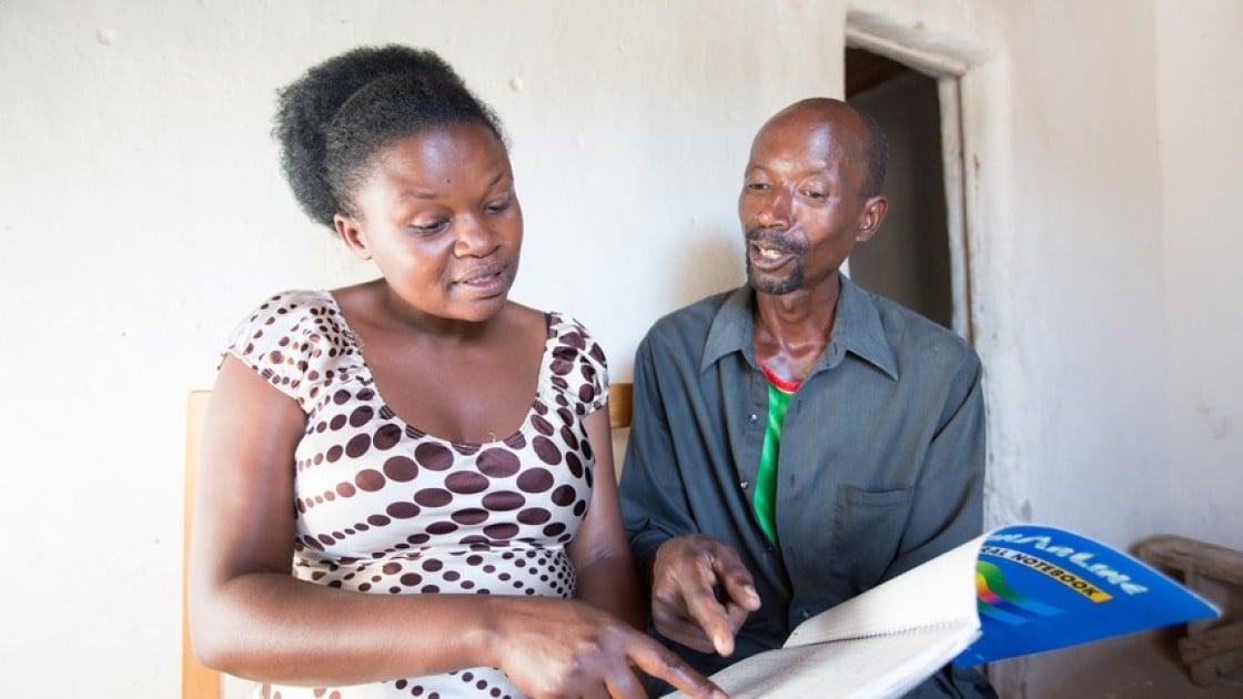 Stanislas Iriboneye participated in Concern’s Graduation programme in Rwanda. He is pictured here with his case worker, Gisèle Umumararungu, who is reviewing his financial plans. Photo: Robin Wyatt / Concern Worldwide, 2015.