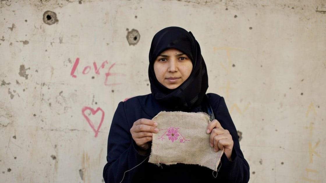 Layal, 27 a refugee from Syria, holding her embroidery as part of a programme to reduce tensions and earn some income through embroidery. Photo by Abbie Trayler-Smith/Panos, Lebanon 2016