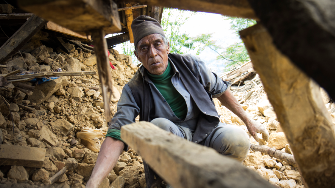 Seventy-year-old Krishna Prasad Sapkota digs through the mud and stones of what used to be his home to see if any belongings can be recovered. Photo taken by Crystal Wells/Concern Worldwide