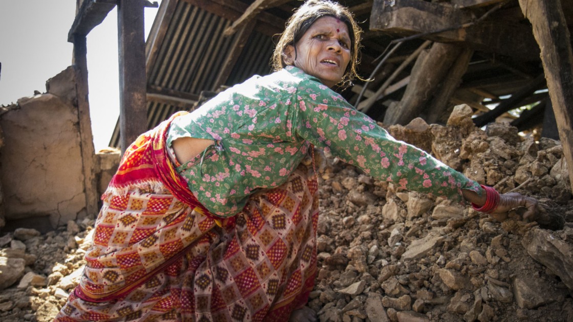 In a Nepalese village, Chandra stands amongst the wreckage of her home. Photo taken by Crystal Wells/Concern Worldwide.