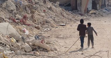 Two children pass by a building totally destroyed by the earthquake in northern Syria
