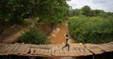 A man uses a small bridge to cross a river in Mikemani village, Tana River County. Photo: Zurich Flood Resilience Alliance/Concern Worldwide