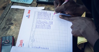 Hands writing details in a cash transfer notebook