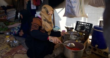 Reem* (30) prepares food for her husband Jaafar* (32) and her children inside their tent in the Ahl al-Khair camp, Syria.