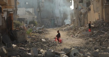 Child on tricycle cycles through destroyed buildings in Gaza