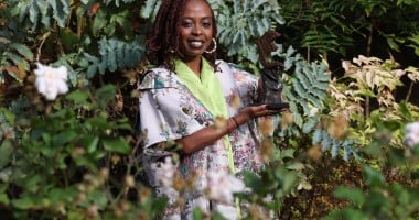 Women of Concern honouree, Berabose Aline Joyce with her award against leave backdrop