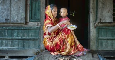 Mitali Mondal is feeding nutritious food to her eighteen months old daughter, Mahi. Every month mothers of the Haldi Bunia community get together once, arrange nutritious meals for their small kids, and feed them together. This session helped mothers to teach each other nutritious meals for their growing children. Several mothers get together and support with the cooking steps. The mother group receives ingredients from the Collective Responsibility, Action, and Accountability for Improved Nutrition (CRAAIN