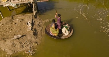 A boy transports people on his curry frying pan across the flooded waters in Jhuddo town of District Mirpurkhas of Sindh, Pakistan, following the devastating floods in 2022.