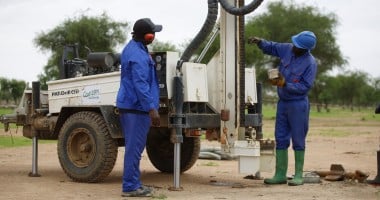 Two men with a machine which is boring a hole into the ground