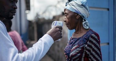 A staff member of the CBCA Virunga Hospital checks a visitor's temperature using a contactless infrared thermometer, before allowing her access to the hospital in Goma, DRC