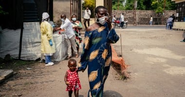 A woman wearing a mask as a preventive measure enters Kyeshero Hospital after passing a checkpoint for hand washing and health screening in Goma