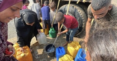 People gather to fill containers with clean water from a tank.