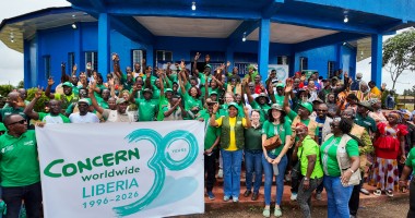 Around 60 people dressed in the green of Concern Worldwide, outside a blue building in Buchanan, LIberia.