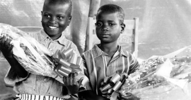 Two children hold flowers at the Runda transition camp in Rwanda. Photo: Concern Worldwide (1997)