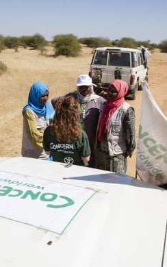 Concern's Nicola Brennan chats with staff members while the team adjust the straps on a load of supplies on their way to Um Shalaya health centre in Central Darfur
