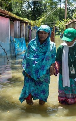A Concern team member walks with a flood affected woman