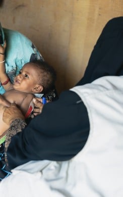 A Community Health Volunteer conducts a nutrition screening of Hamza*during a follow-up visit to his home
