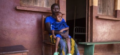 Young boy sitting on mother's lap on wooden chair