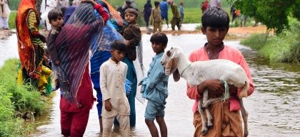 Pakistani people wade through flood water 