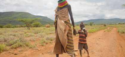 A woman holds her granddaughter's hand as they walk through a village in Kenya