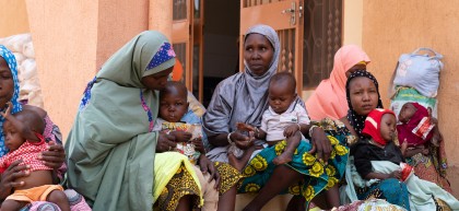 Mothers and their children sit outside recovery centre in Niger
