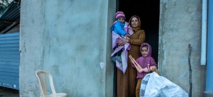 Maram and two of her children in the doorway of the building they live in