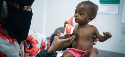 Aalia* (15 months) with her mother, eating nutrition supplements provided at a Concern supported health clinic. Photo: Ammar Khalaf/Concern Worldwide