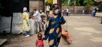 A woman wearing a mask as a preventive measure enters Kyeshero Hospital after passing a checkpoint for hand washing and health screening in Goma