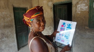 Kumba Tabe Mansaray wife of the Town Chief hanging a Concern Worldwide printed COVID-19 flyer at her residence in Bassaia Village Tonkolili District Sierra Leone Photo: Mohamed Saidu Bah / Concern Worldwide.