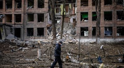 Man walks in front of destroyed building in Ukraine