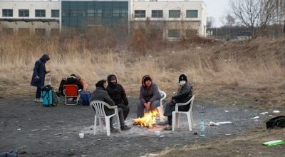 People sitting around small fire at Polish border