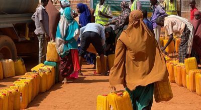 Somali woman walking to a water truck carrying containers to be filled