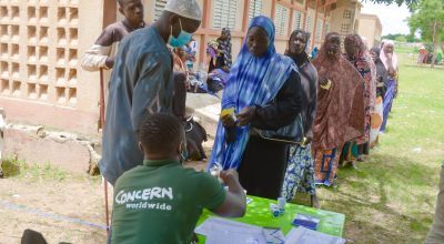 People signing for and receiving kits from the Concern team at Ramesim site, Burkina Faso. The support included unconditional multi-purpose cash transfers and hygiene promotion campaigns. Photo: Jean-Paul Ouedraogo / Concern Worldwide.