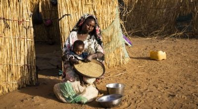 Nigerien woman with her baby, sorting through grain