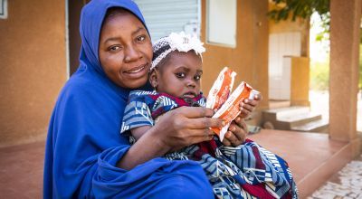 Nigerien mother and her baby holding packets of ready-to-use therapeutic food (RUTF)