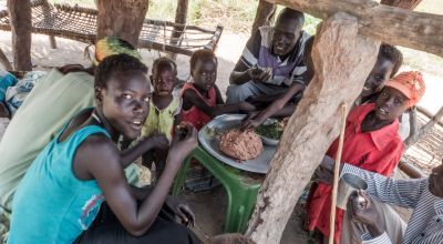 South Sudanese family eating sorghum paste and pumpkin leaves