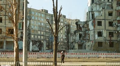 A woman walks down Naberezhna Peremohy Street in Dnipro in front of an apartment building levelled by a missile attack, March 2023.
