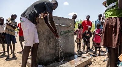 Teachers and children using Concern-installed tap outside school to wash hands
