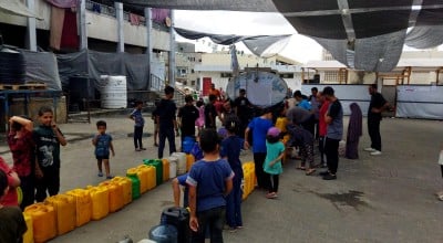People queuing with water containers at a water truck in North Gaza