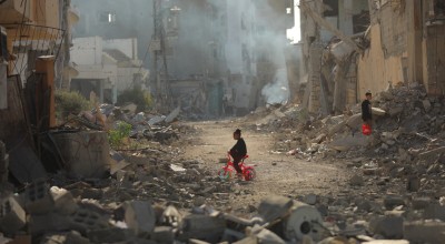 Child on tricycle cycles through destroyed buildings in Gaza