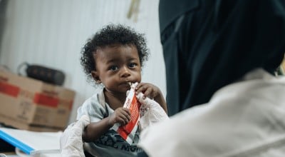 Basam* (10 months) eating nutritional supplements at Concern supported health clinic in one of the displacement camps in Lahj Governorate, Yemen