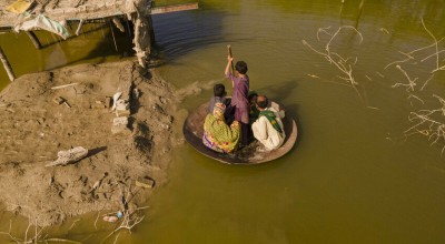 A boy transports people on his curry frying pan across the flooded waters in Jhuddo town of District Mirpurkhas of Sindh, Pakistan, following the devastating floods in 2022.