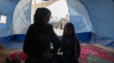 Amira* sits with her youngest child in a tent she calls home, she is one of the 11 million people who have been displaced within Syria during 15 years of conflict. Photo: Gavin Douglas/Concern Worldwide