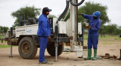 Two men with a machine which is boring a hole into the ground